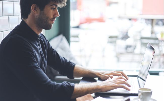 Young business owner sets up his business in a coffee shop
